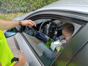 Zdjęcie przedstawiające policjanta oraz osobę otrzymującą mandat za popełnione wykroczenia.