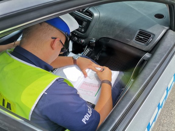 Zdjęcie przedstawiające policjanta oraz osobę otrzymującą mandat za popełnione wykroczenia.