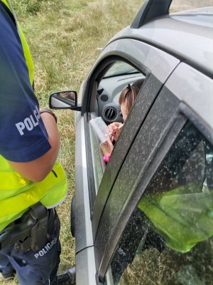 Zdjęcie przedstawiające policjanta oraz osobę otrzymującą mandat za popełnione wykroczenia.