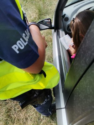 Zdjęcie przedstawiające policjanta oraz osobę otrzymującą mandat za popełnione wykroczenia.