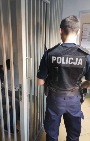 Zdjęcie kolorowe przedstawiające policjanta oraz osobę zatrzymaną.