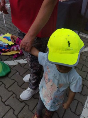 Zdjęcie przedstawiające dziecko z czapką na głowie z napisem &quot;Mamo, Tato, Tutaj jestem!&quot;