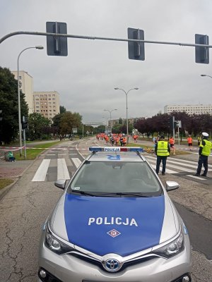 Zdjęcie przedstawiające radiowóz oraz policjantów zabezpieczających bieg.