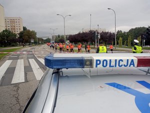 Zdjęcie przedstawiające radiowóz oraz uczestniczki biegu.