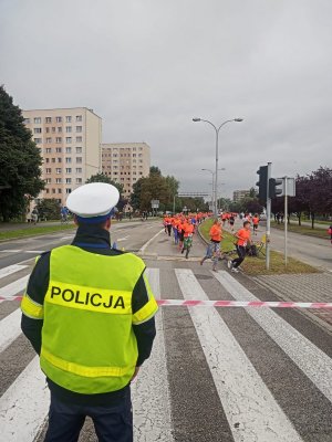 Zdjęcie przedstawiające policjanta ruchu drogowego oraz uczestniczki biegu.