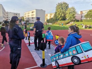 Zdjęcie przedstawiające  policjantów i dzieci w trakcie korzystania z mobilnego miasteczka ruchu drogowego.