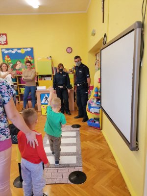 Zdjęcie przedstawiające policjantów i dziecko uczące się korzystania z przejścia dla pieszych.