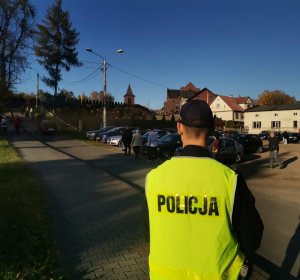 Zdjęcie przedstawiające policjanta pełniącego służbę w rejonie cmentarza.