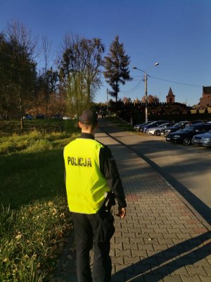 Zdjęcie przedstawiające policjanta pełniącego służbę w rejonie cmentarza.