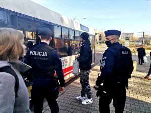 Zdjęcie kolorowe, przedstawiające policjantów w trakcie przyjazdu autobusu.