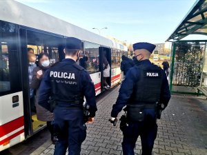 Zdjęcie kolorowe, przedstawiające policjantów na przystanku autobusowym.