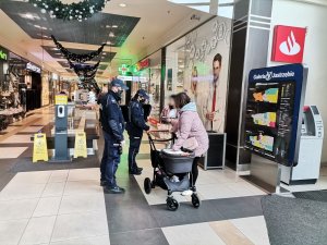 Zdjęcie przedstawiające policjantów w galerii oraz osoby kontrolowane.