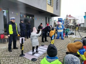 Zdjęcie przedstawiające policjanta ruchu drogowego, który pokazuje jak przechodzić przez przejście dla pieszych.