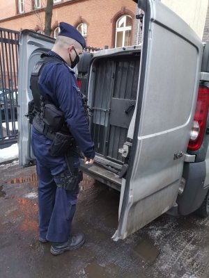 Zdjęcie przedstawiające policjanta oraz radiowóz.