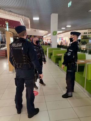 Zdjęcie policjantów w galerii oraz osoby legitymowanej.