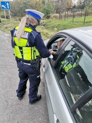 Zdjęcie policjantki, która kontroluje pojazd osobowy.