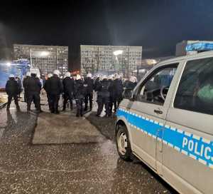 Zdjęcie przedstawiające policjantów zabezpieczających wejście na stadion kibiców przyjezdnych.