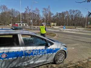 Zdjęcie przedstawiające policjanta ruchu drogowego oraz radiowóz w trakcie działań.