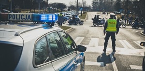 Zdjęcie przedstawiające policjanta ruchu drogo oraz radiowóz w trakcie zabezpieczenia.