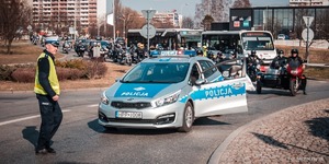 Zdjęcie przedstawiające radiowóz, policjanta ruchu drogowego oraz motocyklistów.