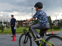 Zdjęcie przedstawiające rowerzystę w trakcie egzaminu oraz policjanta ruchu drogowego.