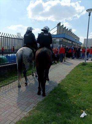 Zdjęcie przedstawiające policję konną oraz kibiców.