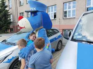 Zdjęcie przedstawiające Sznupka oraz przytulające się dzieci.