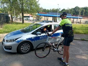 Zdjęcie przedstawiające policjanta w radiowozie oraz rowerzystę.