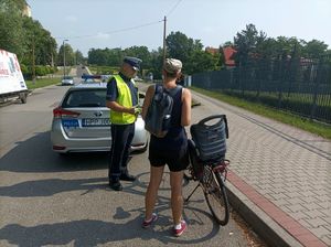 Zdjęcie przedstawiające radiowóz policyjny oraz rowerzystę.