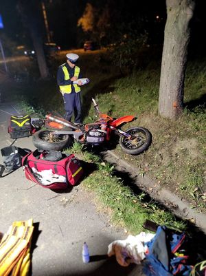 Zdjęcie przedstawiające policjanta ruchu drogowego oraz uszkodzony motocykl.