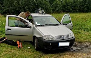 Zdjęcie osoby zatrzymanej oraz policjantów oraz samochodu fiat.