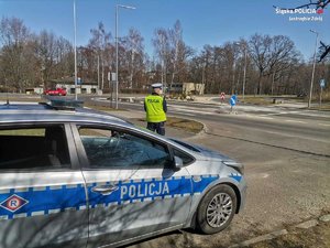 Zdjęcie przedstawiające policjanta oraz radiowóz.