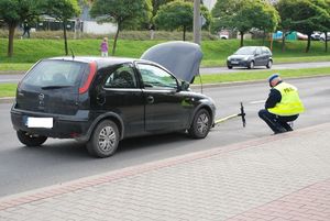 Zdjęcie przedstawiające samochód opel oraz hulajnogę uszkodzoną oraz policjanta ruchu drogowego.