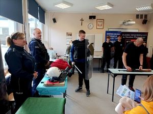 Zdjęcie kolorowe przedstawiające ucznia poznającego umundurowanie policjanta.