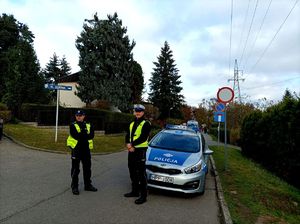 Zdjęcie kolorowe przedstawiające policjanta ruchu drogowego oraz dzielnicowego przy cmentarzu.