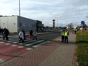 Zdjęcie kolorowe przedstawiające policjanta ruchu drogowego oraz ucznia klasy mundurowej przy przejściu dla pieszych.