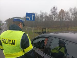 Zdjęcie policjanta ruchu drogowego oraz  mężczyznę w zatrzymanym pojeździe.