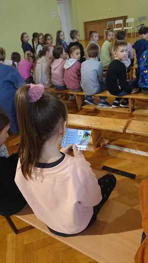 Zdjęcie przedstawiające siedzące dzieci w trakcie prelekcji.