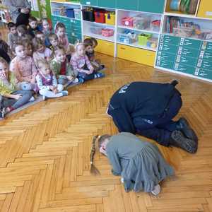 Zdjęcie przedstawiające policjanta oraz dziecko prezentujące pozycję żółwia.