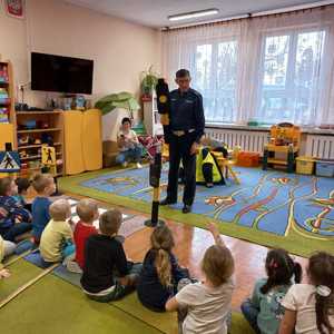 Zdjęcie przedstawiające policjanta oraz dzieci w sali przedszkolnej.