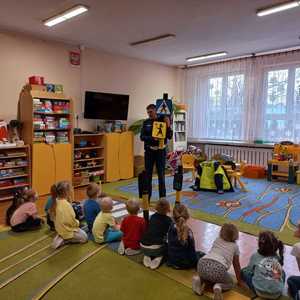 Zdjęcie przedstawiające policjanta oraz dzieci w sali przedszkolnej.