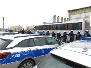 Zdjęcie przedstawiające policjantów, radiowozy oraz autobus.