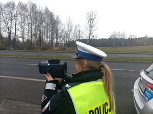 Zdjęcie przedstawiające policjntkę w trakcie wykonywania pomiaru na urządzenia do mierzenia prędkości,.