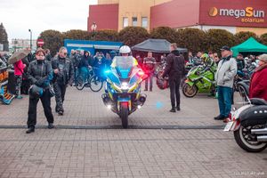 Zdjęcie przedstawiające uczestników rozpoczęcia sezonu oraz policjanta na motocyklu.