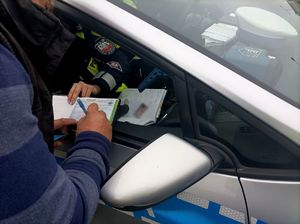 Zdjęcie przedstawiające moment podpisywania mandatu karnego przez kierowcę.