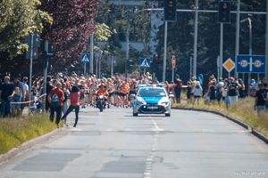 Zdjęcie przedstawiające radiowóz ruchu drogowego oraz biegnące kobiety.