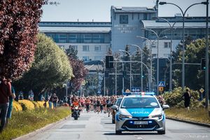 Zdjęcie przedstawiające radiowóz ruchu drogowego oraz uczestniczki biegu.