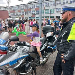 Zdjęcie przedstawiające policjanta oraz dziewczynkę na motocyklu.