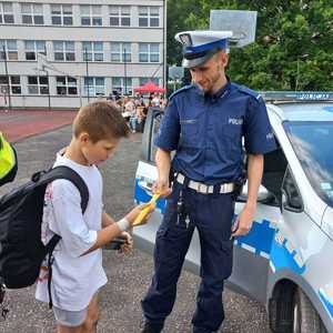 Zdjęcie przedstawiające policjanta oraz chłopca trzymającego odblask.