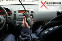 Zdjęcie przedstawiające policjantów w radiowozie. Jeden z policjantów trzyma radiostację.
